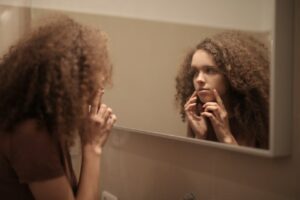 Femme se regardant dans le mirroir pour constater les effets du CBD contre l'acné