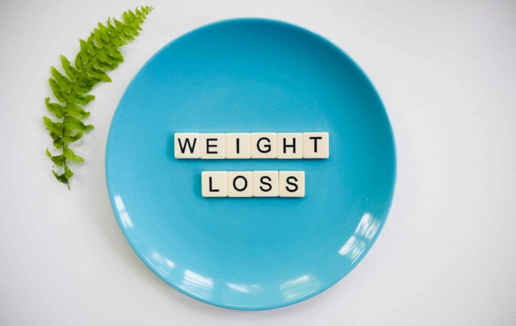 Une assiette bleue contenant les mots sous forme de pieces de scrabble "Weight loss" pour illustrer la perte de poids et le CBD