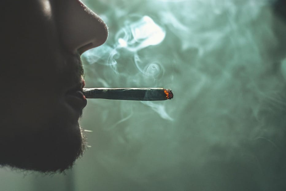 Gros plan sur une personne fumant un joint avec du THC