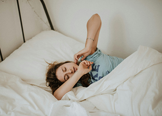 Une femme endormie dans un lit symbolisant le sommeil que lui apporte une infusion au CBD